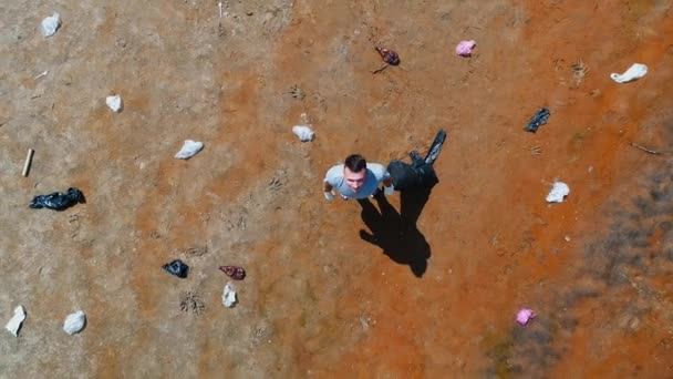 Vue aérienne du dessus de l'homme qui se tient le long des déchets plastiques sur les rives d'une rivière polluée — Video