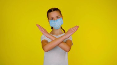 Teen girl in medical holds her arms crossed on yellow background