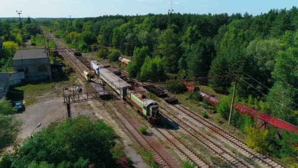 Вид с воздуха на свалку заброшенных ржавых поездов среди леса в городе Припять — стоковое видео