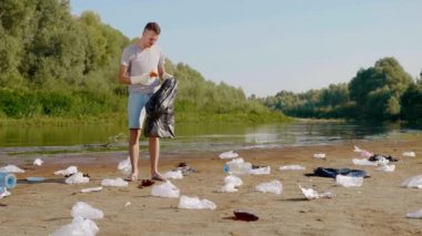 Man collects plastic trash on banks of polluted river and shows thumbs up