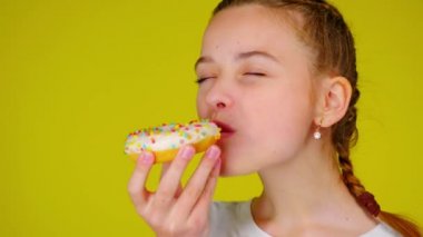 Teenage girl in a white T-shirt bites a donut and don't likes it.