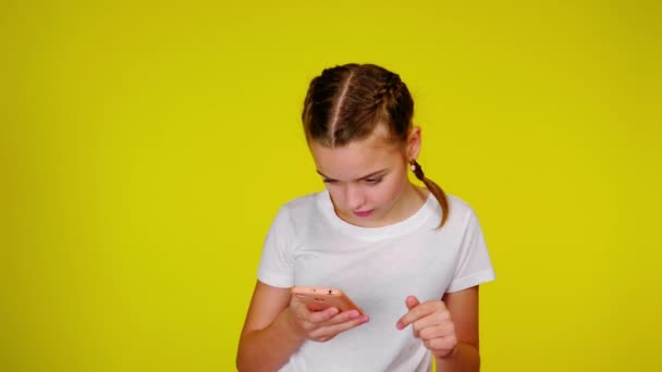 Teenage girl in a white T-shirt is using a pink smartphone. — Stock video