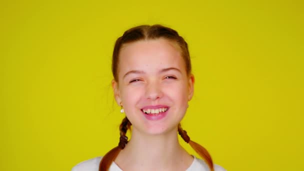 Happy teenage girl in a white T-shirt is laughing and looks to camera. — Stock video