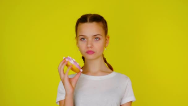 Teenage girl in a white T-shirt shows a pink donut — Stock Video