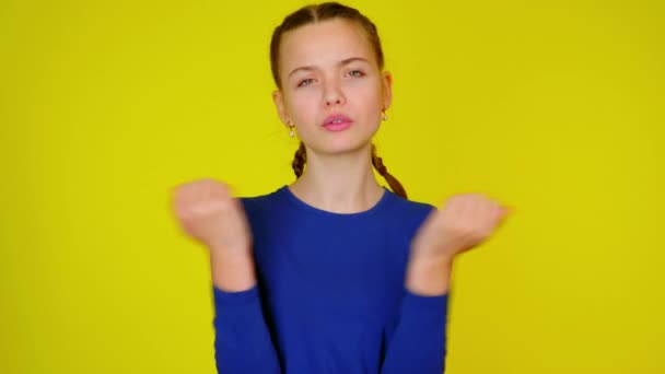 Tiener meisje in blauw pullover maakt een gebaar met twee handen. — Stockvideo