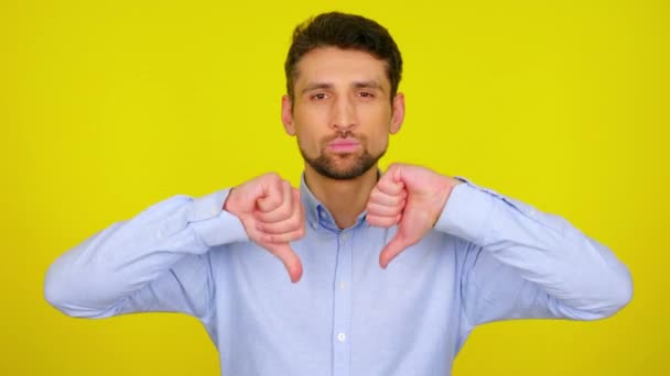 Young man in light blue shirt shows dislike, thumb down. — Stock Video