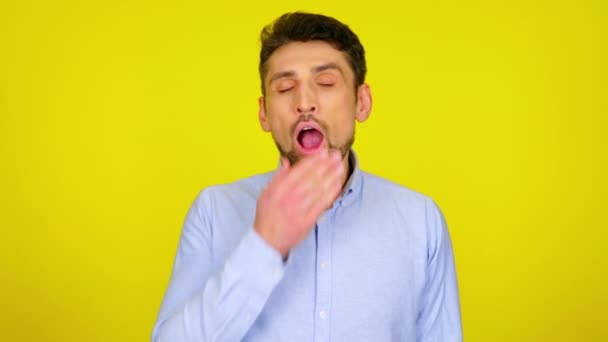 Tired young man in light blue shirt is yawns, wants to sleep. — Stock videók