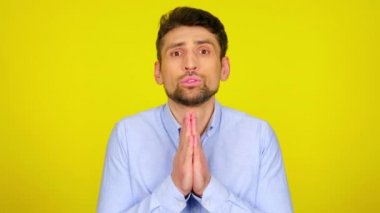 Young man in light blue shirt is praying, asks for something.