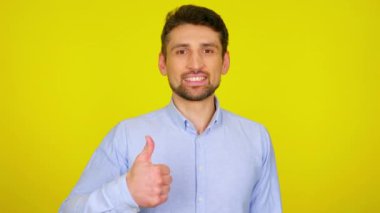 Young man in light blue shirt is smiling and shows thumb up, like.