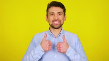 Young man in light blue shirt is smiling and shows thumb up, like.