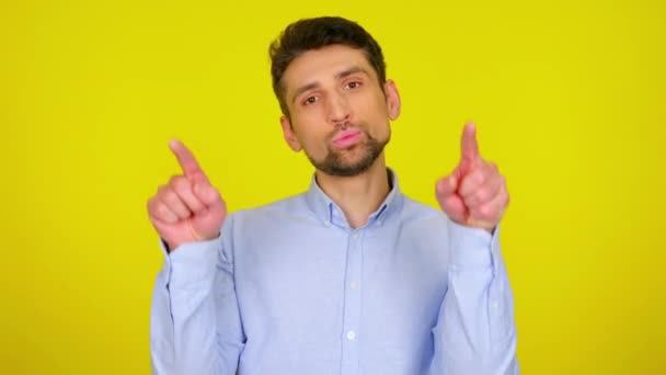 Sweet young man in light blue shirt draws a heart in the air with his fingers. — Stock videók