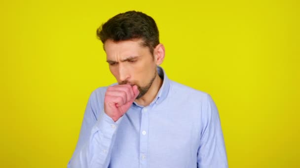 Young man in light blue shirt is coughs and covers his mouth with his fist. — Stock video