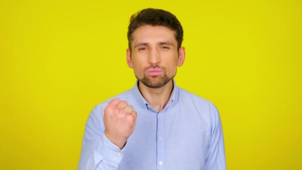 Angry young man in light blue shirt is shows a fist. — Stock Video