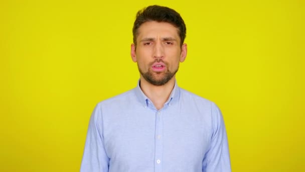 Young man in light blue shirt is sneezes and covers his mouth with his fist. — Stock videók