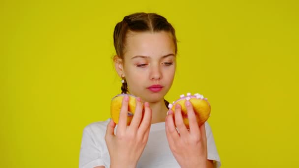 Teenage girl in a white T-shirt shows donuts and smiles — Stock Video