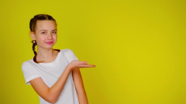 Teenagermädchen im weißen T-Shirt zeigt auf einen Ort für Text — Stockvideo