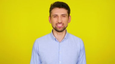 Açık mavi gömlekli kızgın genç adam dişlerini sırıtıyor..