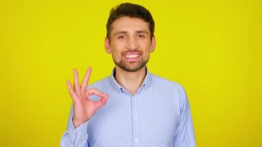 Açık mavi gömlekli genç adam gülümsüyor ve iyi görünüyor.