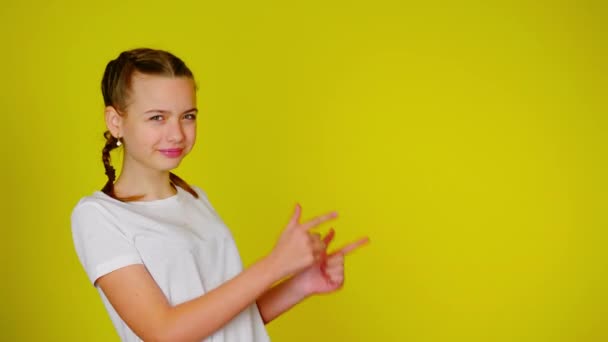 Adolescente em uma camiseta branca aponta para um lugar para texto . — Vídeo de Stock