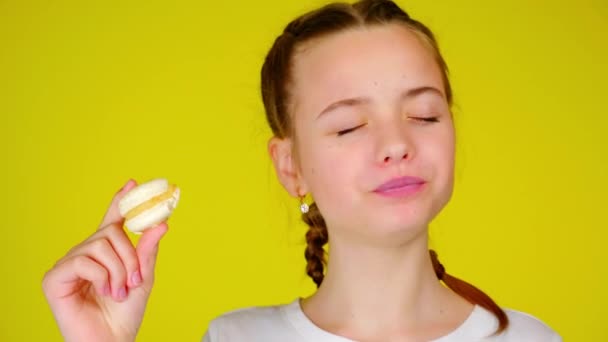 Adolescente chica muerde un macarrón blanco y disfruta de su sabor incomparable — Vídeos de Stock