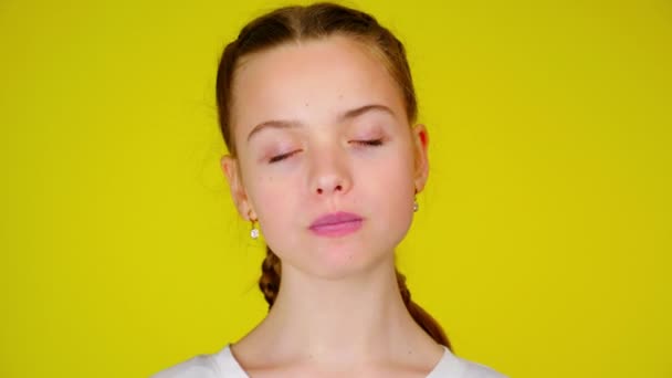 Teenage girl in a white T-shirt chews gum and inflates a bubble — Stock video