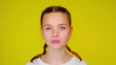 Happy teenage girl in a white T-shirt is laughing and looks to camera