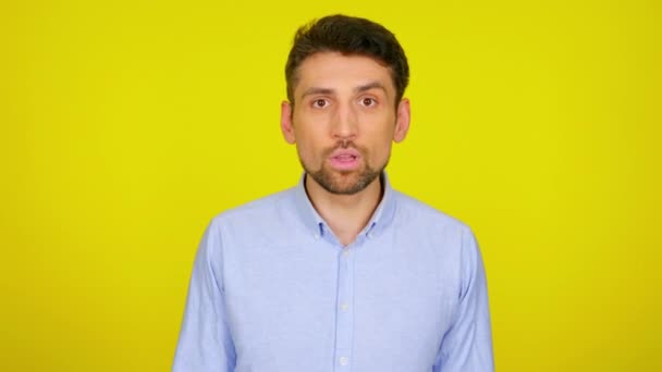 Jongeman in lichtblauw shirt is verrast en bedekt zijn mond met de hand — Stockvideo
