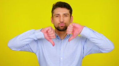 Young man in light blue shirt shows dislike, thumb down.