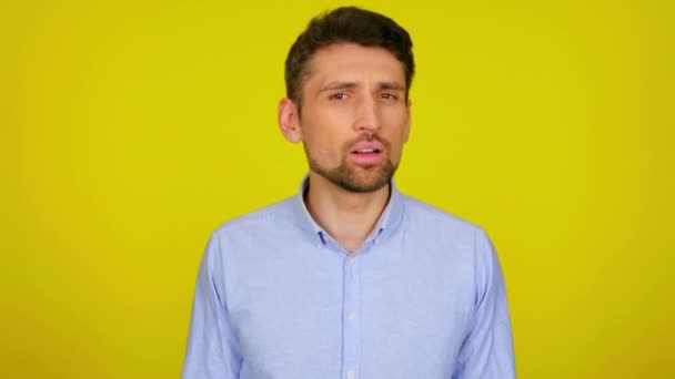 Jongeman in lichtblauw hemd legt een handpalm aan zijn oor, hoort niet, luistert — Stockvideo