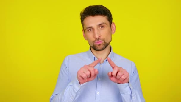 Sweet young man in light blue shirt draws a heart in the air with his fingers. — Stock video