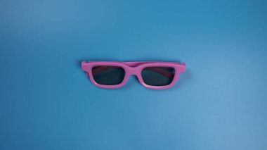 Mavi arka planda film izlemek için pembe 3D gözlükler. Düz Yatay