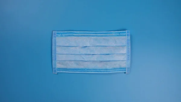 Medical protective mask on a blue background. Face mask that protects against the spread of bacteria and viruses from patients. The outside of the mask, covers the mouth and nose. Coronavirus, Flu