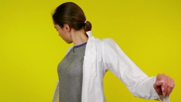 Una giovane donna in una t-shirt grigia, vestendo un camice medico bianco — Video Stock