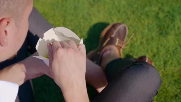 Чоловік тримає в руках екологічний паперовий пакет з їжею та дерев'яною вилкою — стокове відео