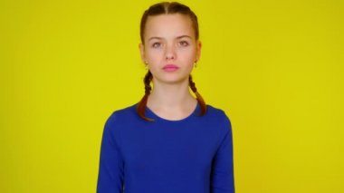 Teenage girl in blue pullover makes a gesture with two hands