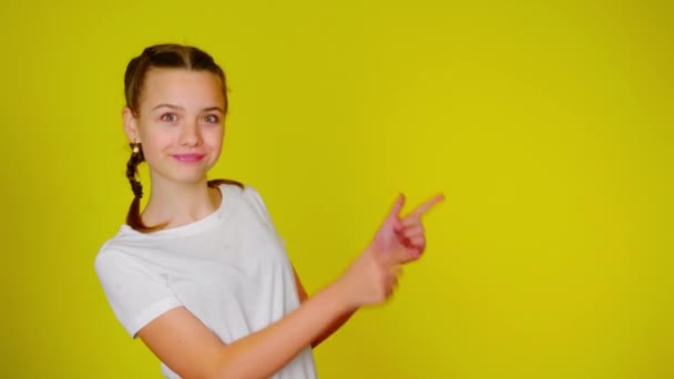 Дівчина-підліток у білій футболці вказує на місце для тексту — стокове відео