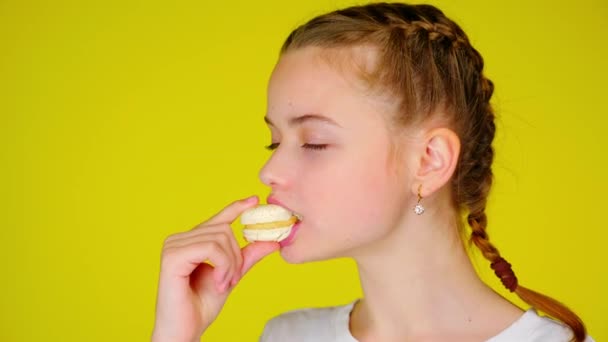 Teenage dívka kousne bílého makróna a má jeho nesrovnatelnou chuť — Stock video