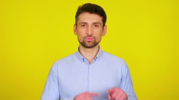 Sweet young man in light blue shirt draws a heart in the air with his fingers — 图库视频影像