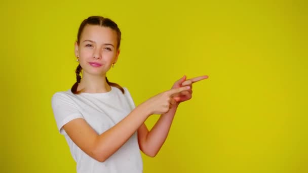 Adolescente em uma camiseta branca aponta para um lugar para texto — Vídeo de Stock