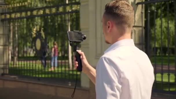 Блогер гуляет по парку со смартфоном, записывающим видео для подписчиков — стоковое видео