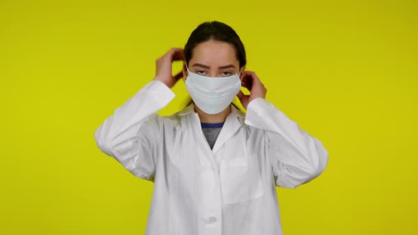 Young woman in white medical coat is wearing a protective mask — Stock Video