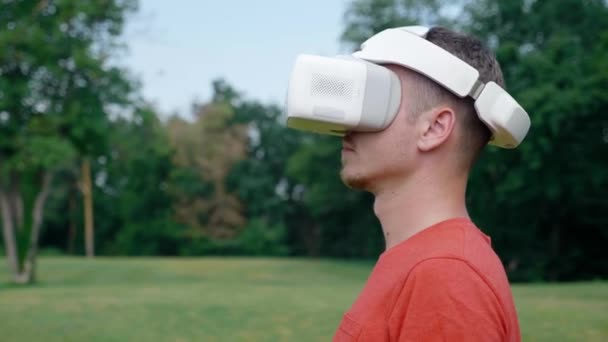 Um homem com um capacete de realidade virtual vira a cabeça para a esquerda — Vídeo de Stock