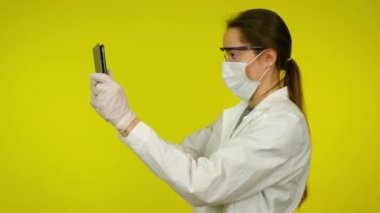 Tıp önlüklü kadın, koruyucu maske tablet aracılığıyla arttırılmış gerçeklik kullanıyor.