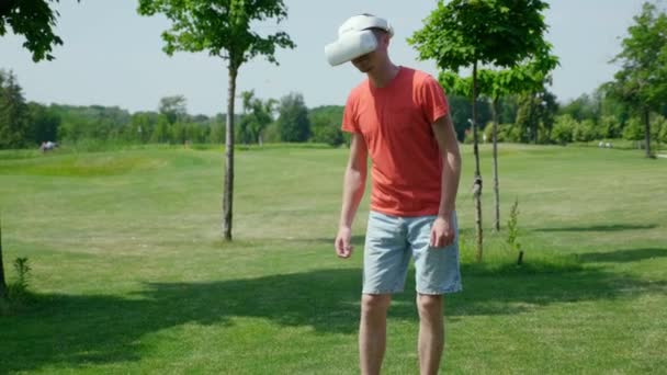Забавный человек танцует в парке в шлеме виртуальной реальности — стоковое видео