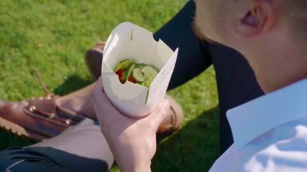 De mens eet groenten met papieren ecologische verpakking met een houten stokje — Stockvideo
