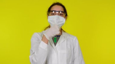 Beyaz elbiseli, koruyucu maskeli genç kadın test tüpüyle dans ediyor.