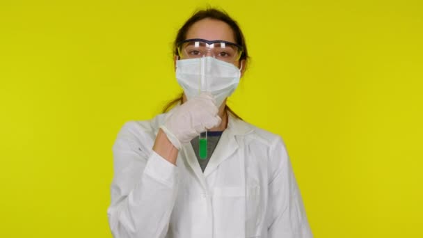 Mujer joven en vestido médico blanco, máscara protectora está bailando con tubo de ensayo — Vídeos de Stock