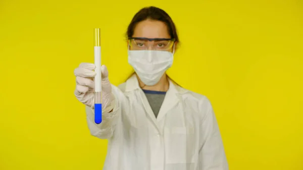 Fille dans un masque médical, lunettes et gants en latex tient dans sa main un tube — Photo