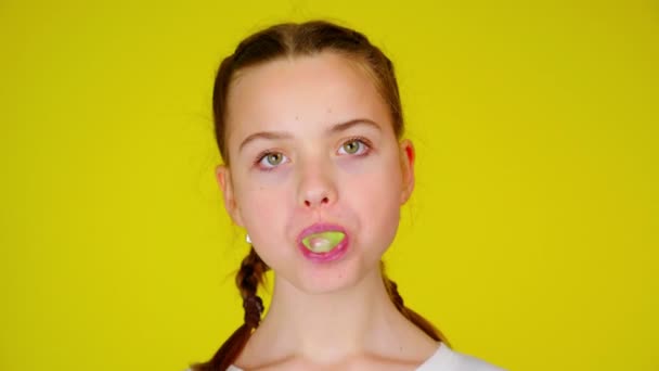 Adolescente menina em uma camiseta branca mastiga chiclete e infla uma bolha — Vídeo de Stock