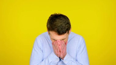 Hasta adam yüzünü hapşırdı ve elleri kopyalanmış sarı bir arka plandaydı.